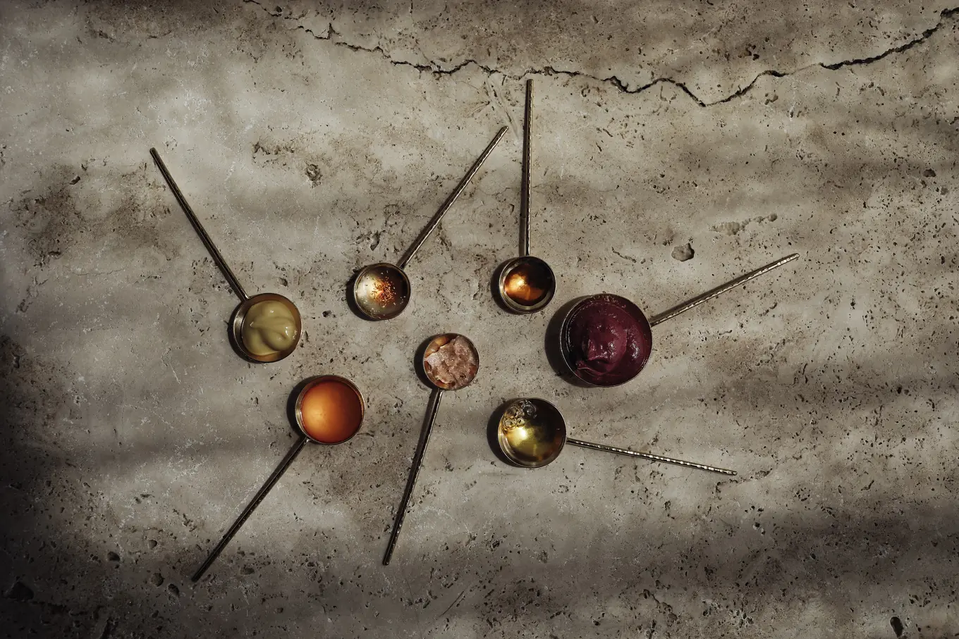 LACUEOR balms and oils on brass spoons, travertine